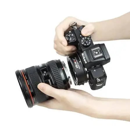 Руки оператора приєднують важкий зум-об'єктив Canon до бездзеркальної камери Nikon через встановлений адаптер Viltrox, фіксуючи байонетне кріплення